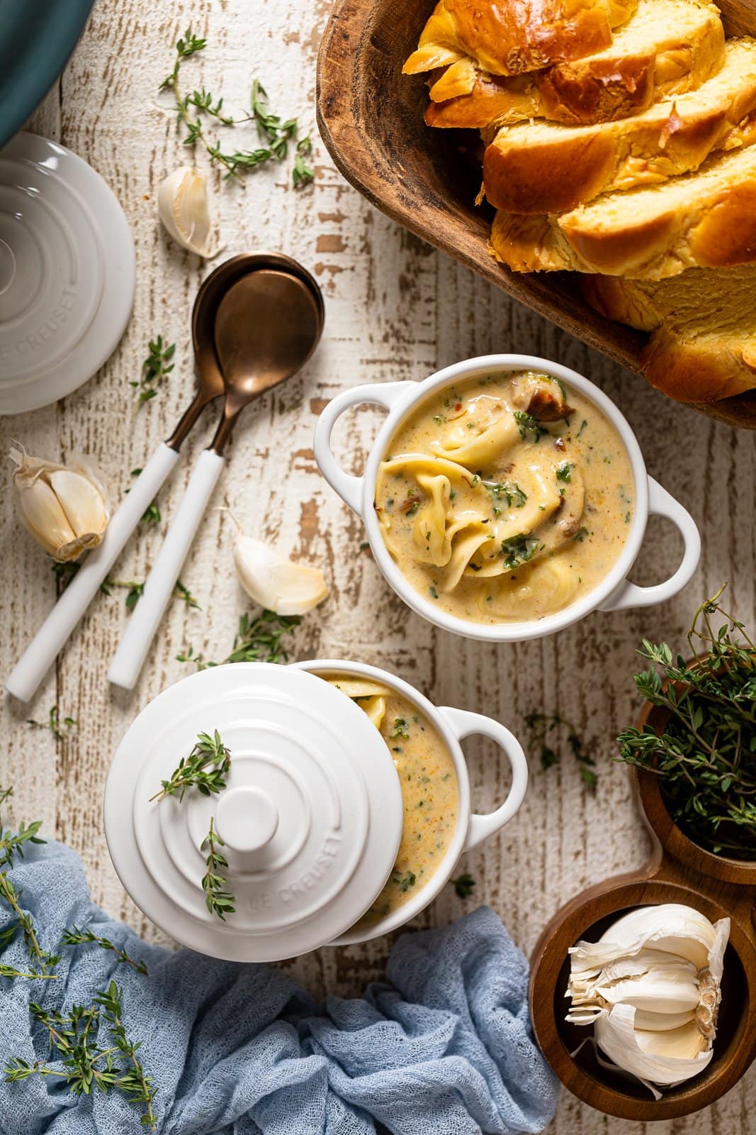 Overhead shot of Creamy Roasted Garlic Tortellini Soup in two small Le Creuset handled bowls