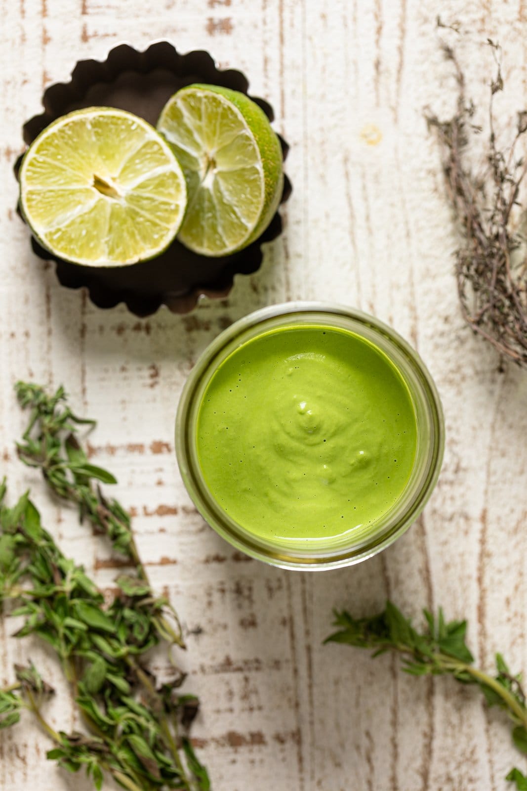 Overhead shot of a jar of Green Goddess sauce and lime halves