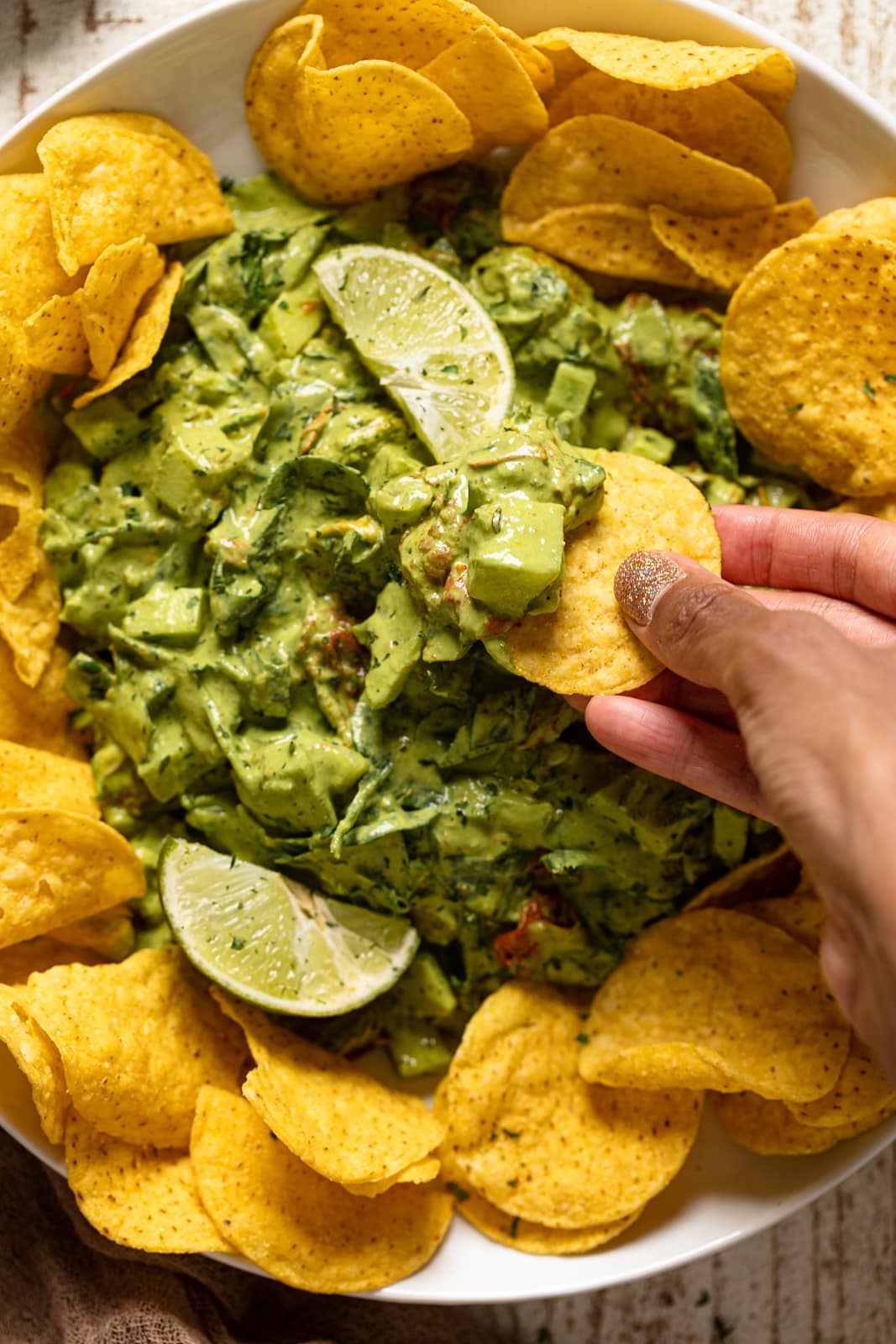 Hand dipping a chip into Green Goddess Salad Dip 