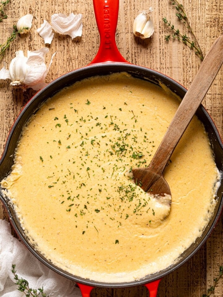 Wooden spoon stirring a pan of Creamy Southern Cheese Grits