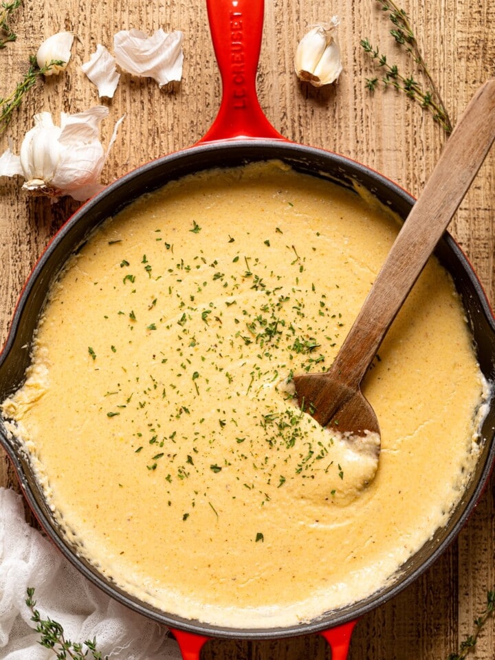 Wooden spoon stirring a pan of Creamy Southern Cheese Grits