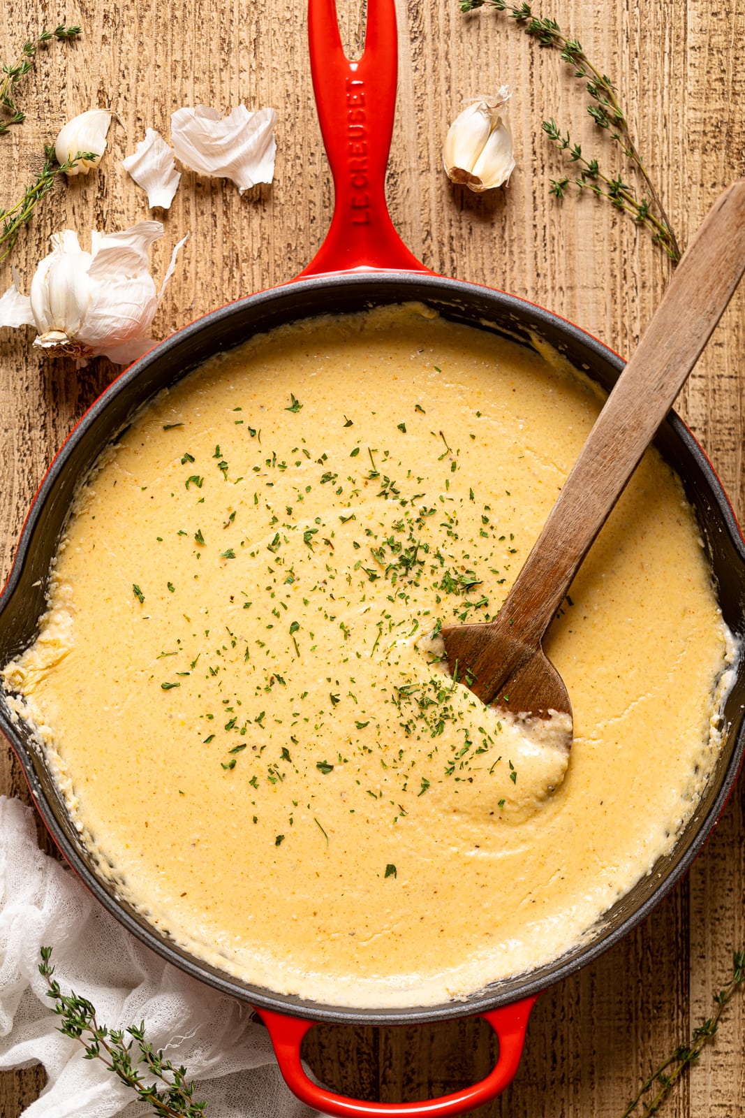 Wooden spoon stirring a pan of Creamy Southern Cheese Grits