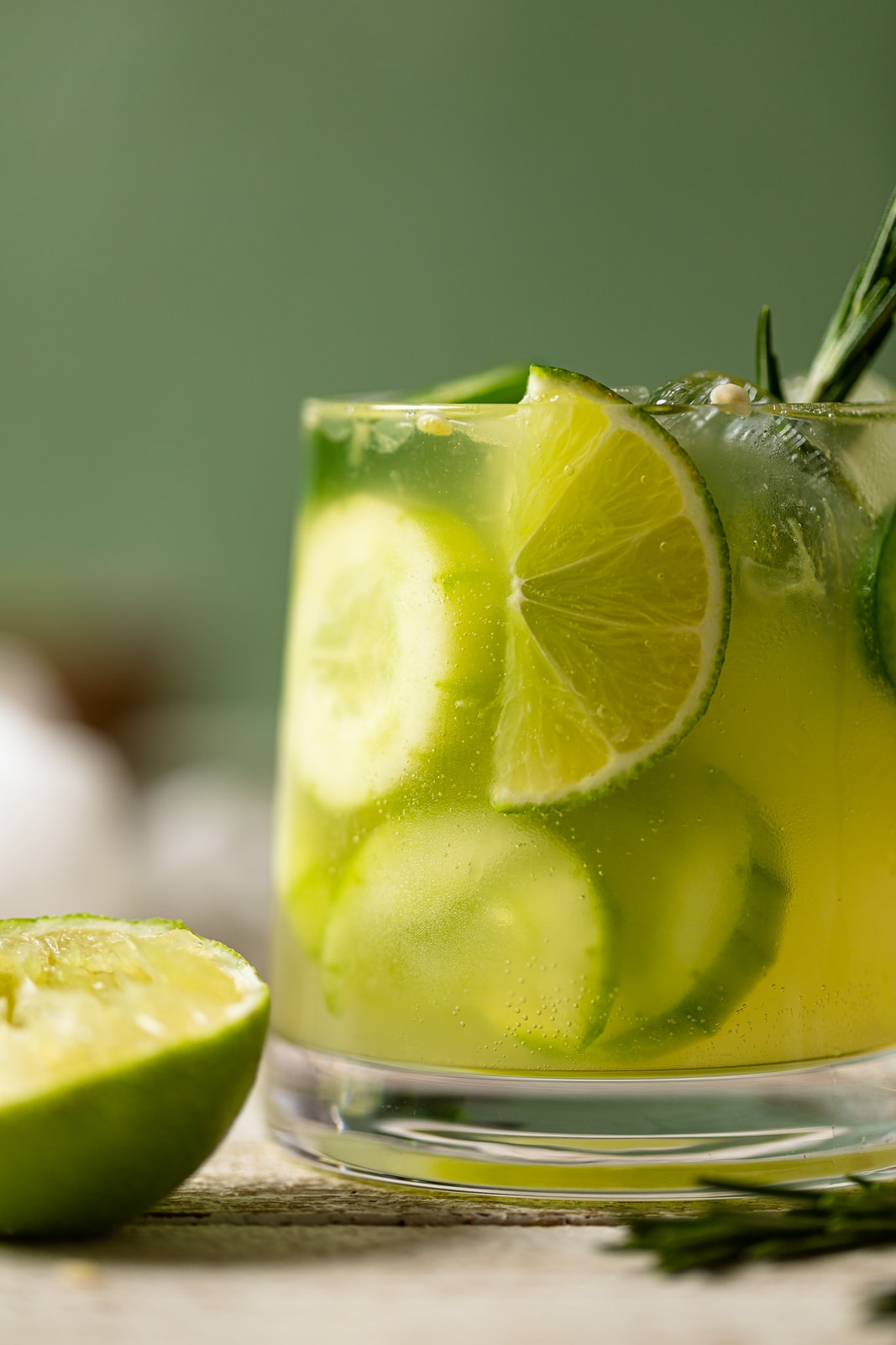 Closeup of a Bright green Spicy Cucumber Mocktail in a small glass stuffed with cucumbers and lime wedges. Non-alcoholic cocktail