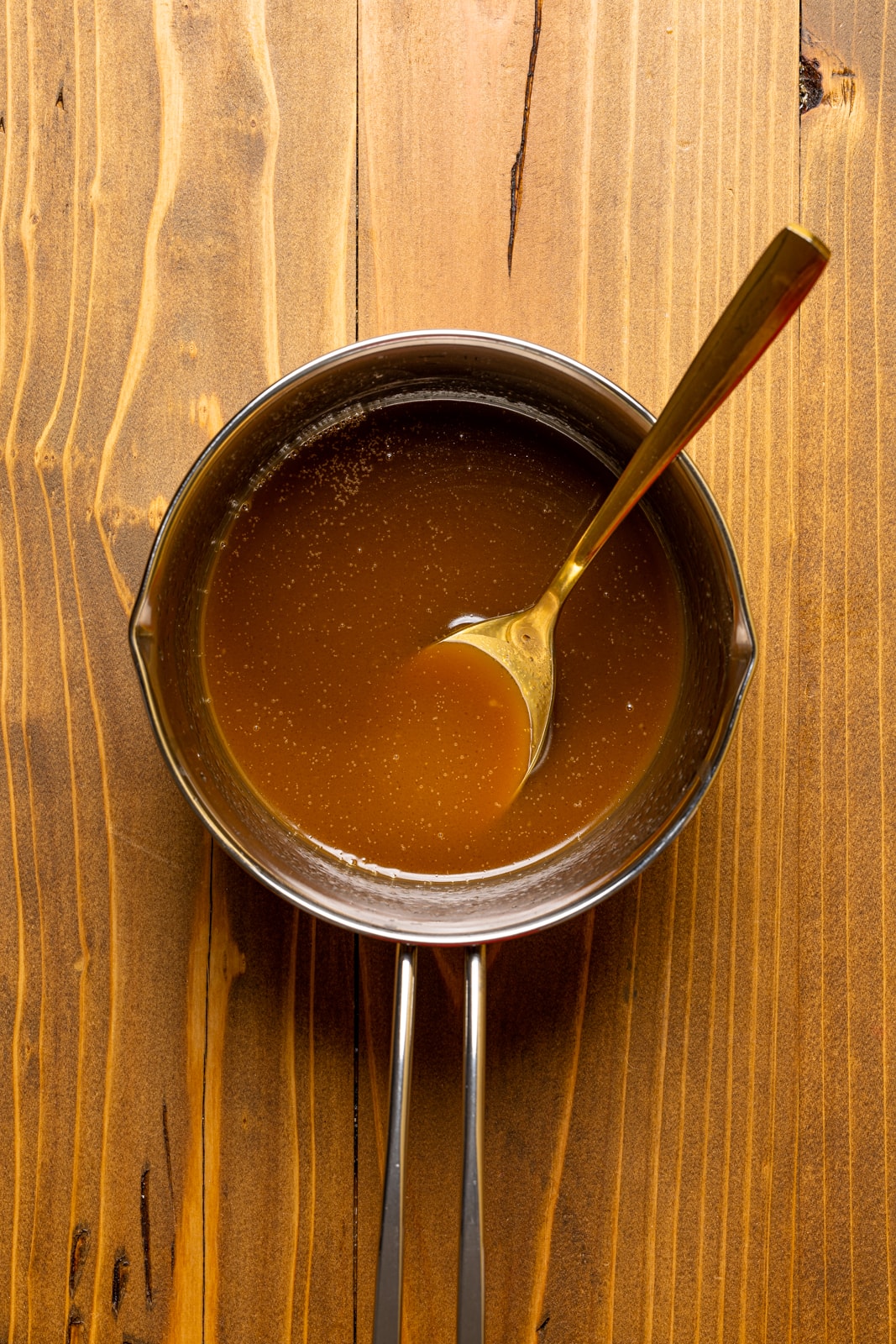 Kahlua substitute in a silver pot with a spoon on a brown wood table.