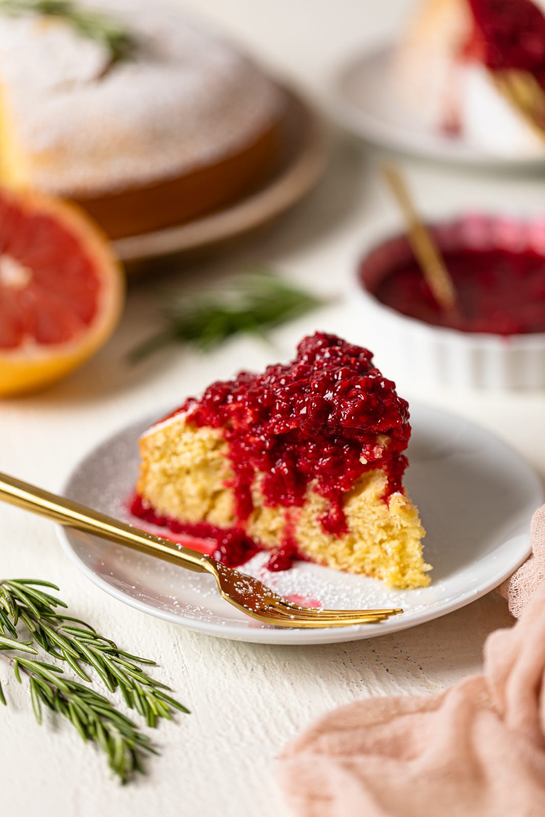 Slice of Grapefruit Olive Oil Cake with Raspberry Compote on a small plate with a fork