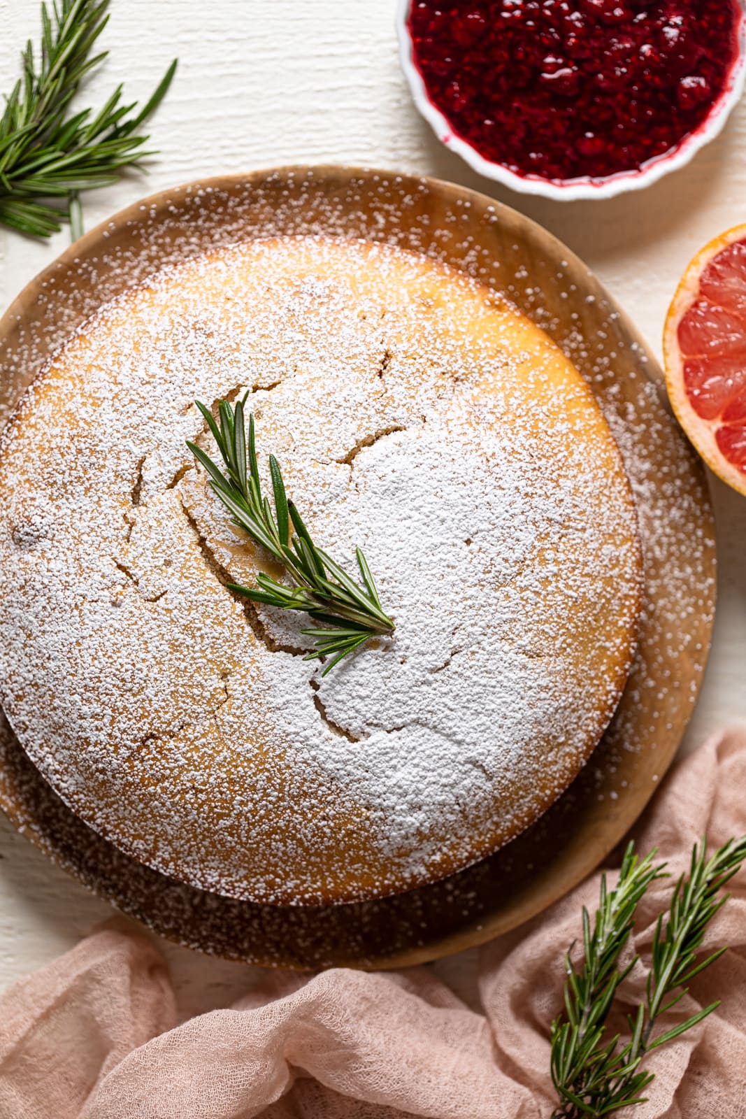 Overhead shot of a Grapefruit Olive Oil Cake on a wooden board, sifted with powdered sugar