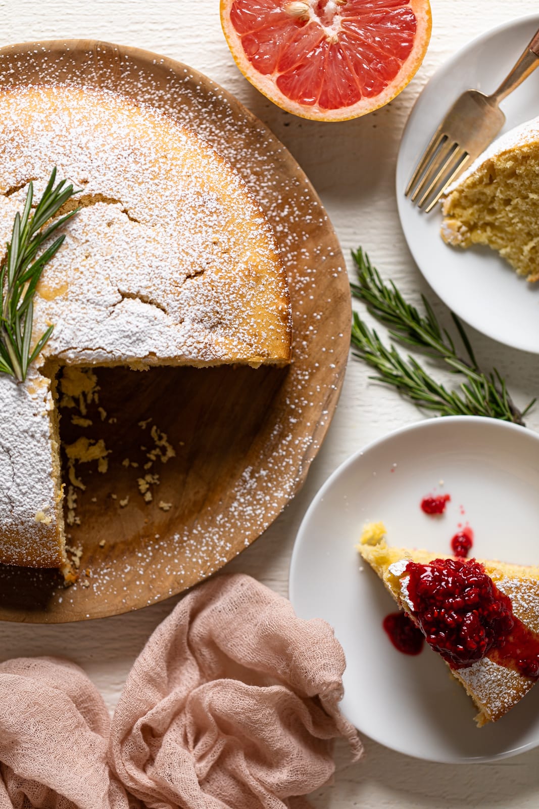 Overhead shot of a Grapefruit Olive Oil Cake on a wooden board, sifted with powdered sugar, and missing some slices