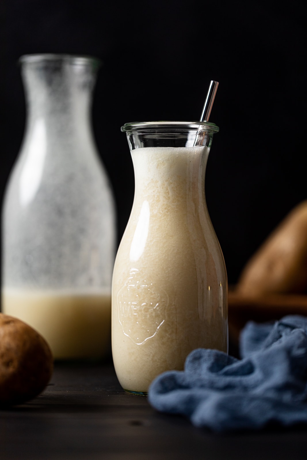 Glass carafe of potato milk with a metal straw