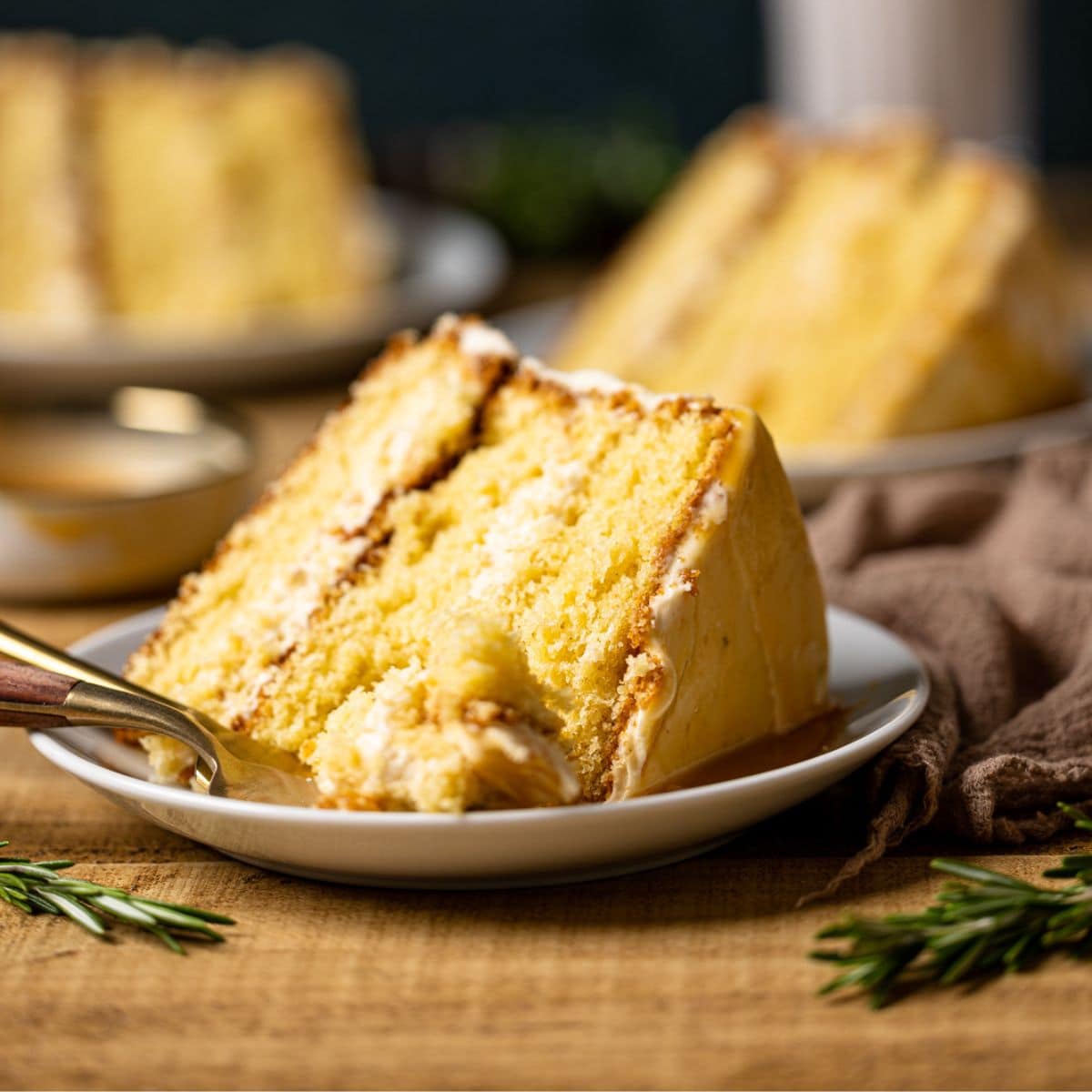 Up close shot of slices of cake on a white plate with a fork on a brown wood table.