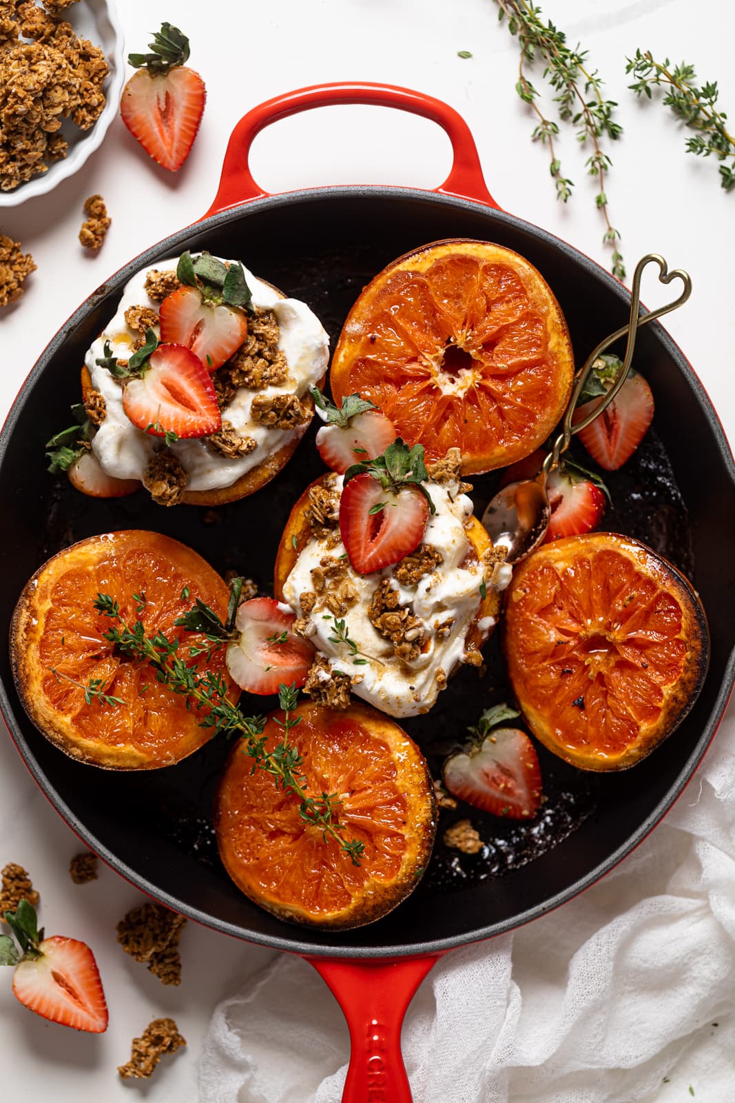 Overhead shot of Broiled Maple Cinnamon Grapefruits with Strawberries, two of which are topped with coconut whipped cream and granola