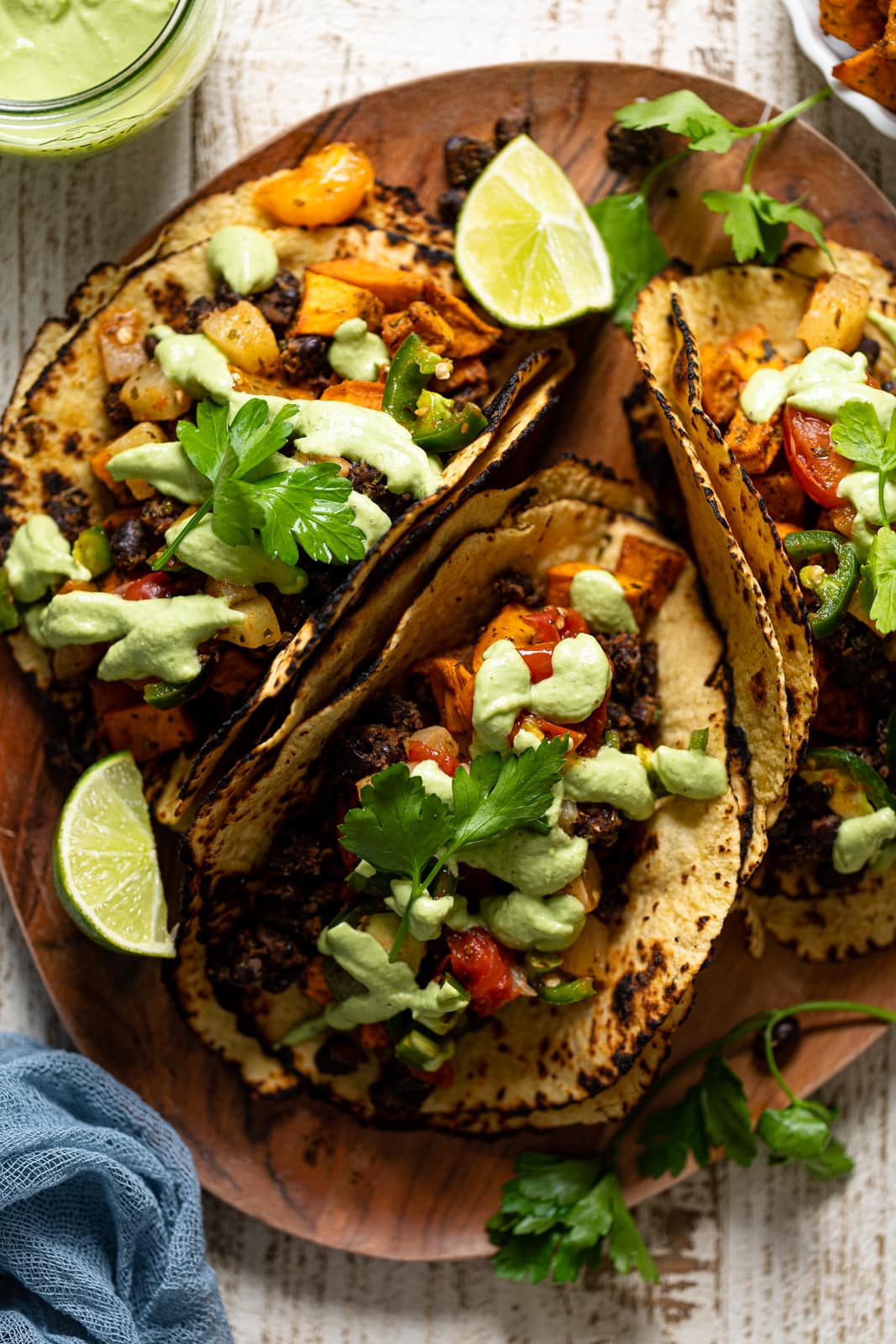 Overhead shot of a wooden board with three Roasted Sweet Potato Black Bean Tacos