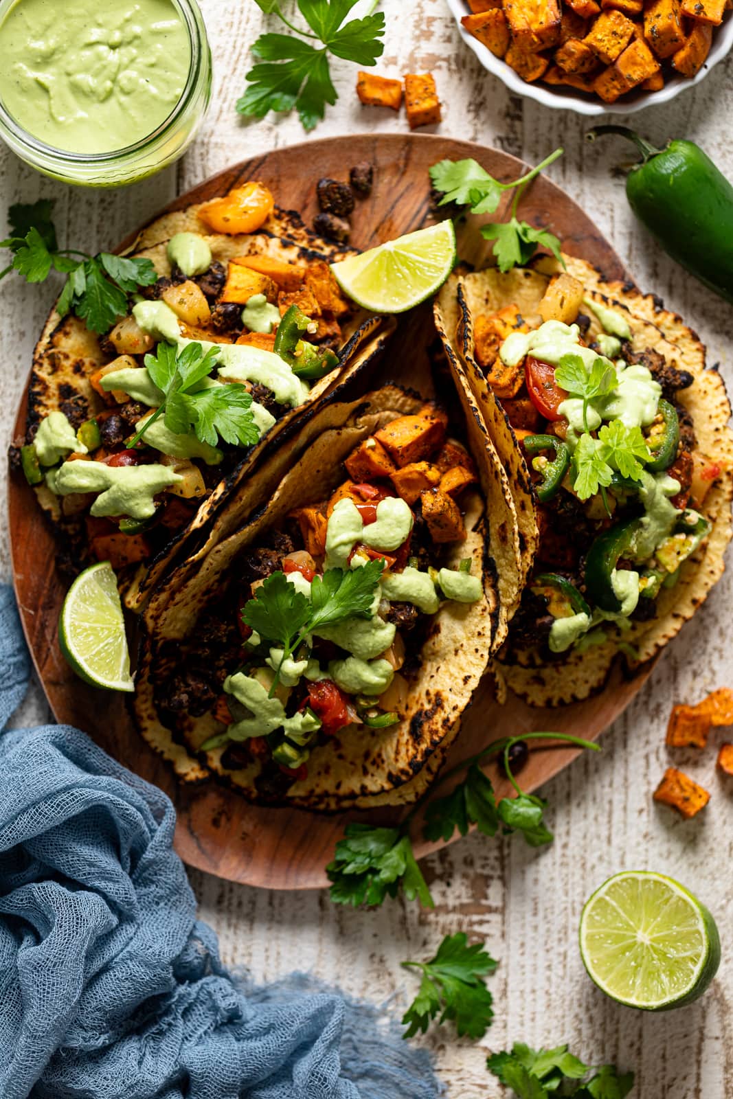 Overhead shot of a wooden board with three Roasted Sweet Potato Black Bean Tacos