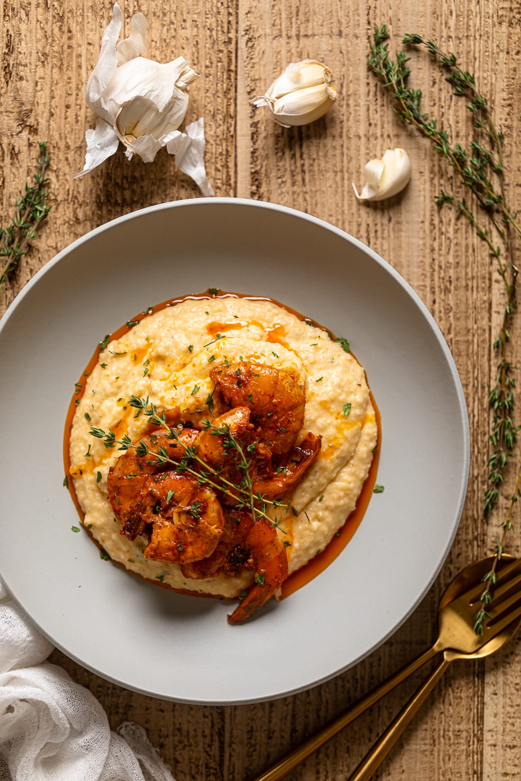 Overhead shot of a plate of Spicy Southern Shrimp and Grits on a wooden surface