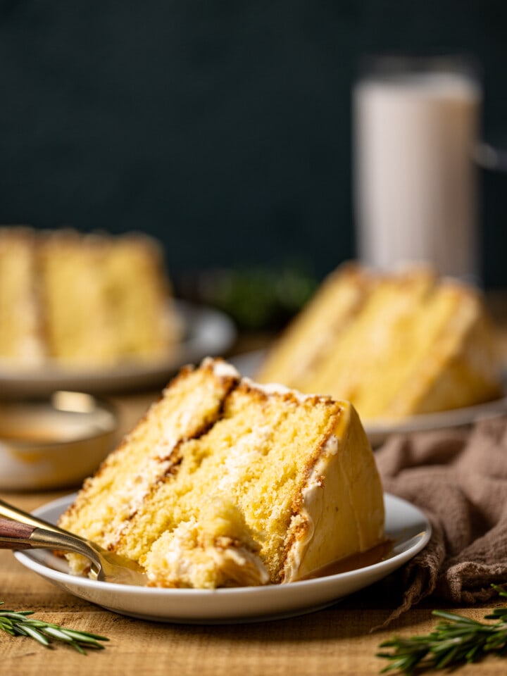 Up close shot of slices of cake on a white plate with a fork on a brown wood table.