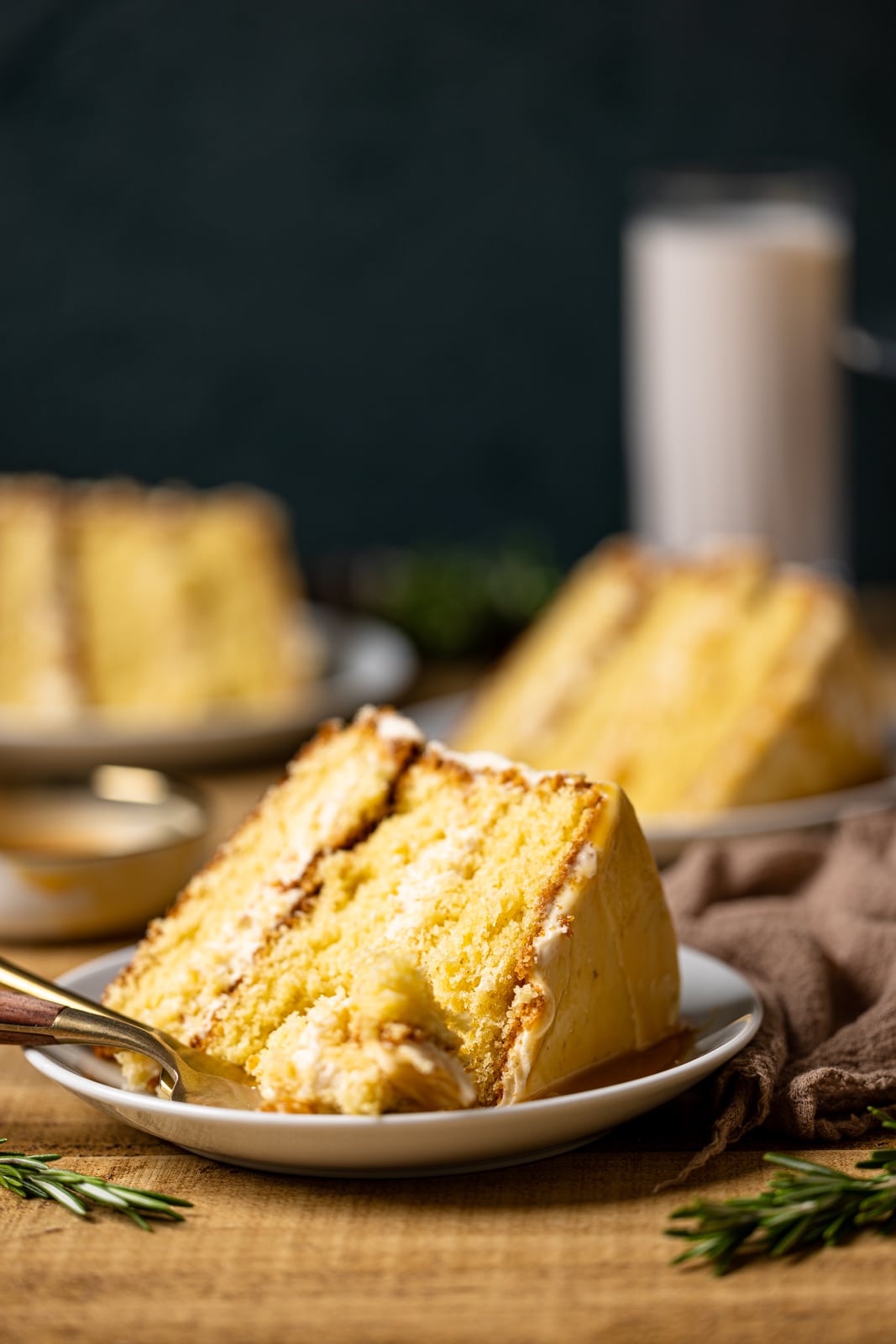 Up close shot of slices of easter cake on a white plate with a fork on a brown wood table.