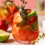 Spicy Grapefruit Jalapeño "Paloma" Mocktail in a small glass with halved strawberries, jalapeno slices, and thyme