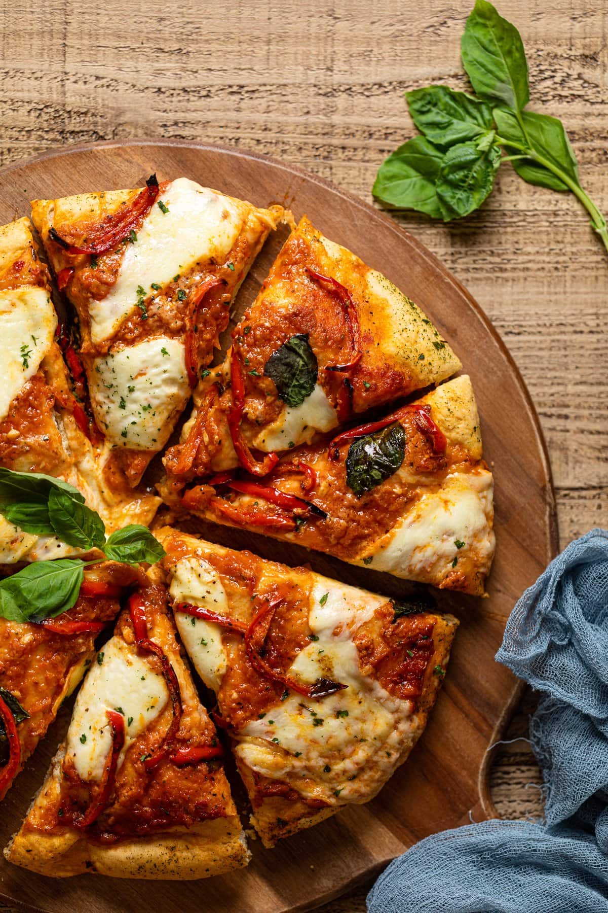 Sliced Vodka Pizza on a wooden board topped with basil leaves