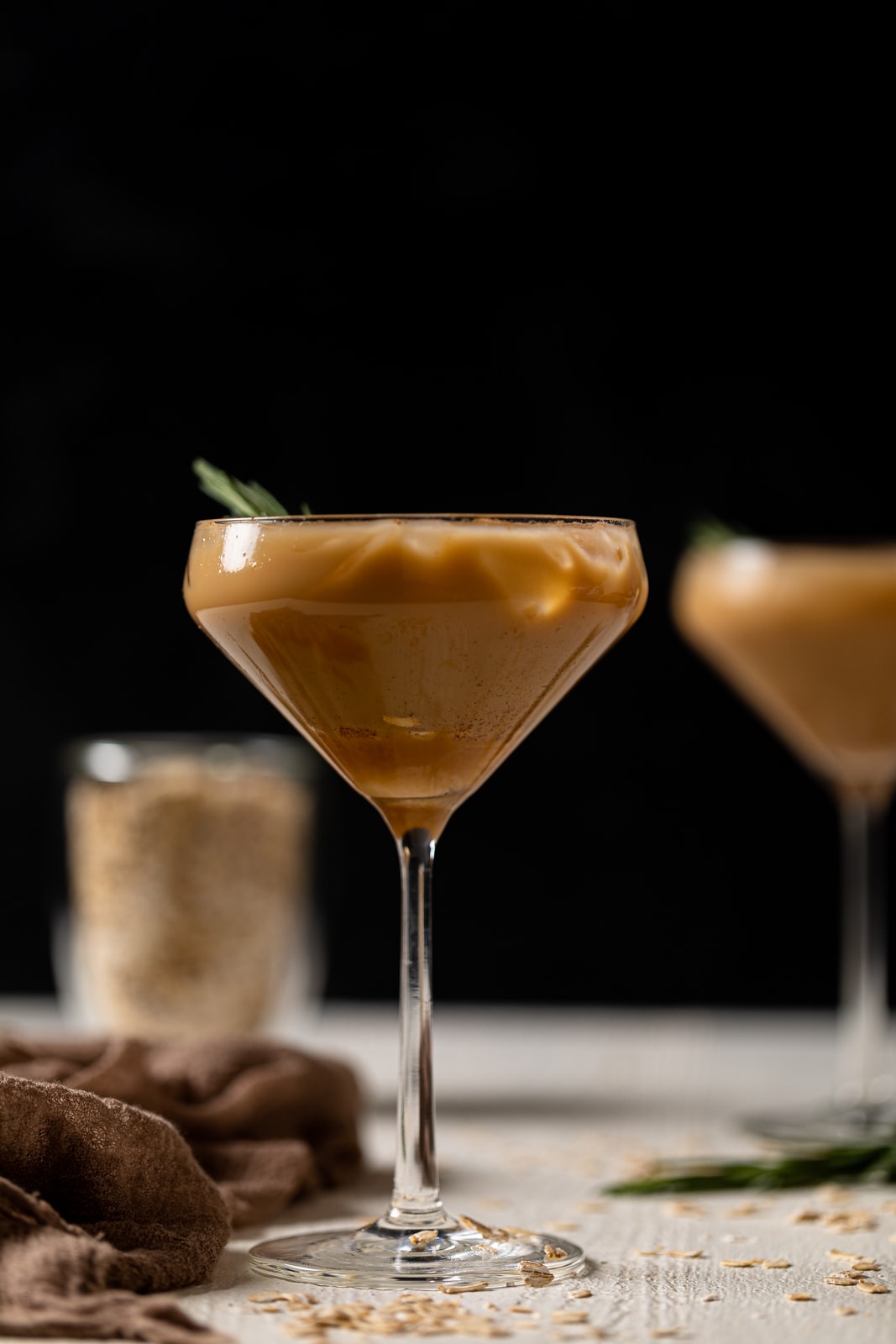 Caramel Oat Latte Mocktail in a long-stemmed glass on a white table