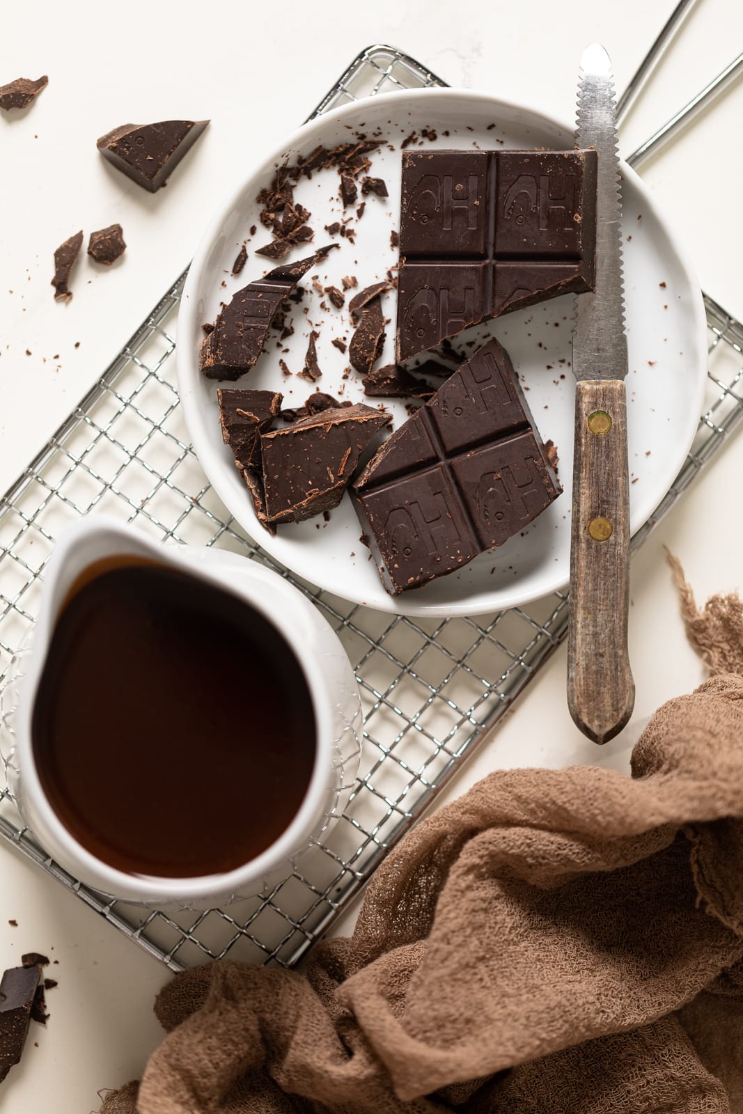 Plate of chopped chocolate next to a small cup of chocolate syrup