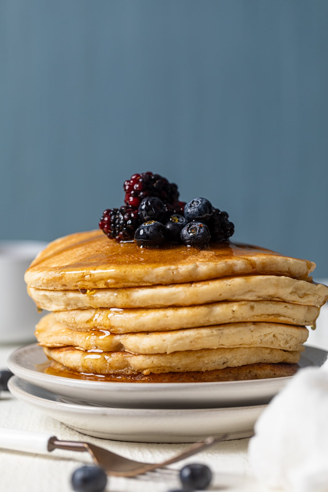 Stack of pancakes topped with berries and syrup