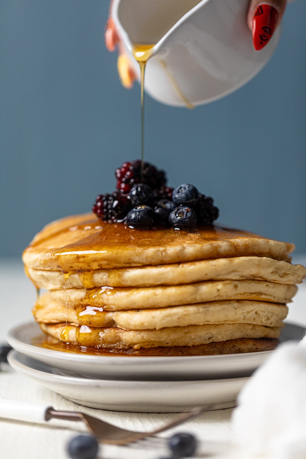 Syrup pouring onto a stack of pancakes