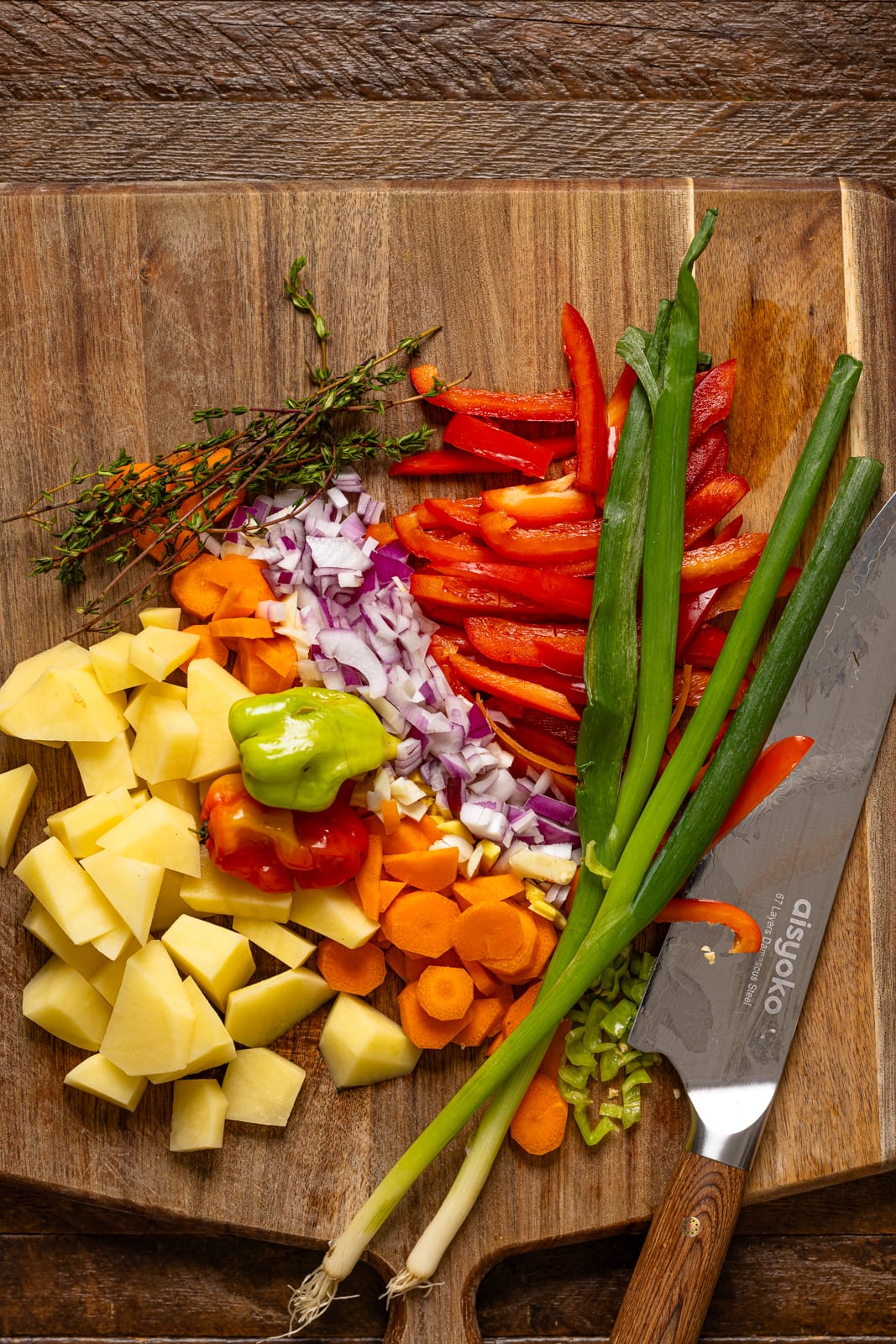 Chopped veggies on a cutting board with a knife.