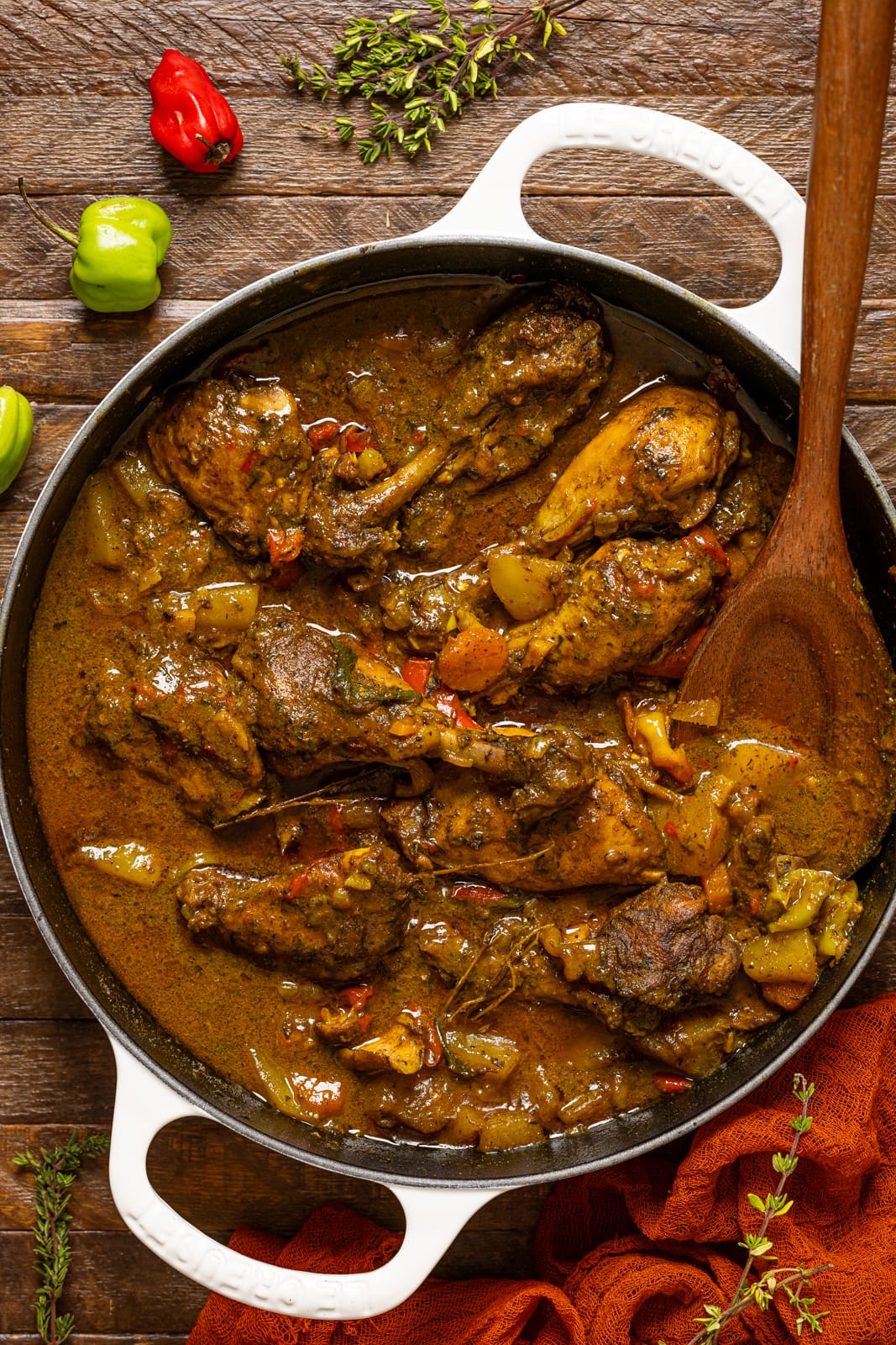 Curry chicken in a white pot with a wooden spoon.