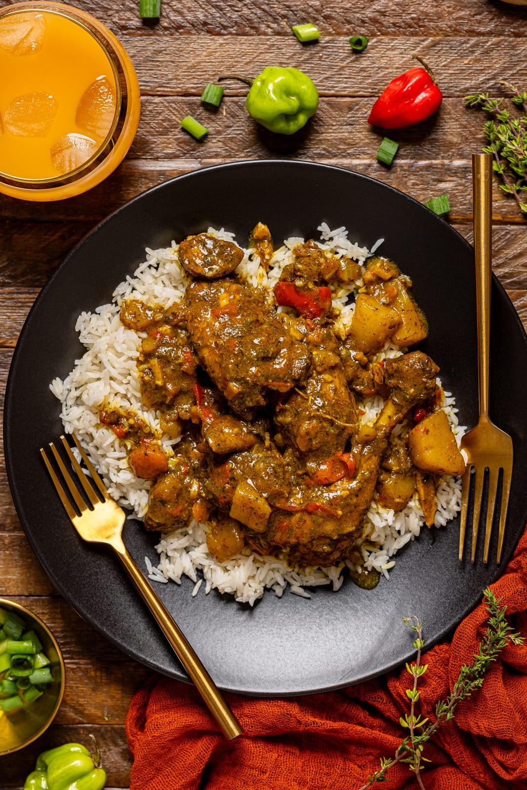 Curry chicken in a black plate with two forks and a side of drink.