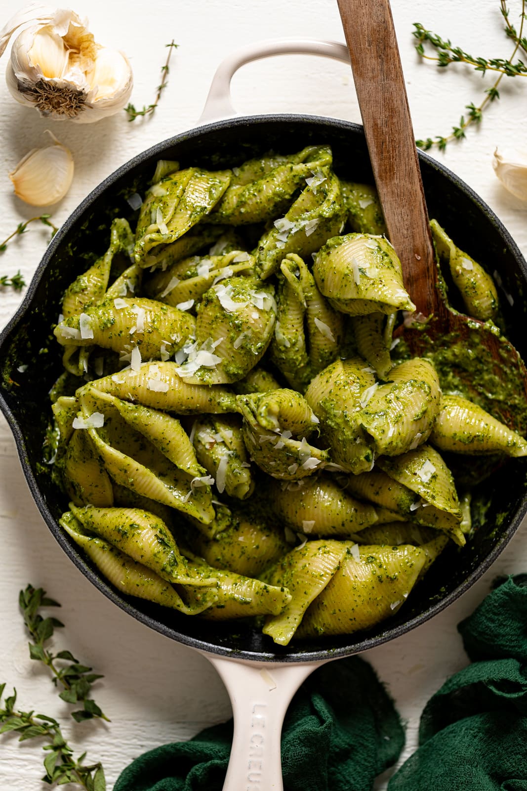 Wooden spoon stirring a skillet of Creamy Roasted Garlic Kale Pasta with Parmesan