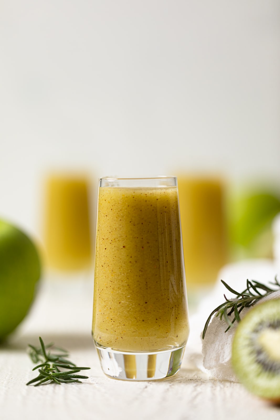 Small glass of Cleansing Apple Kiwi Juice near sprigs of rosemary