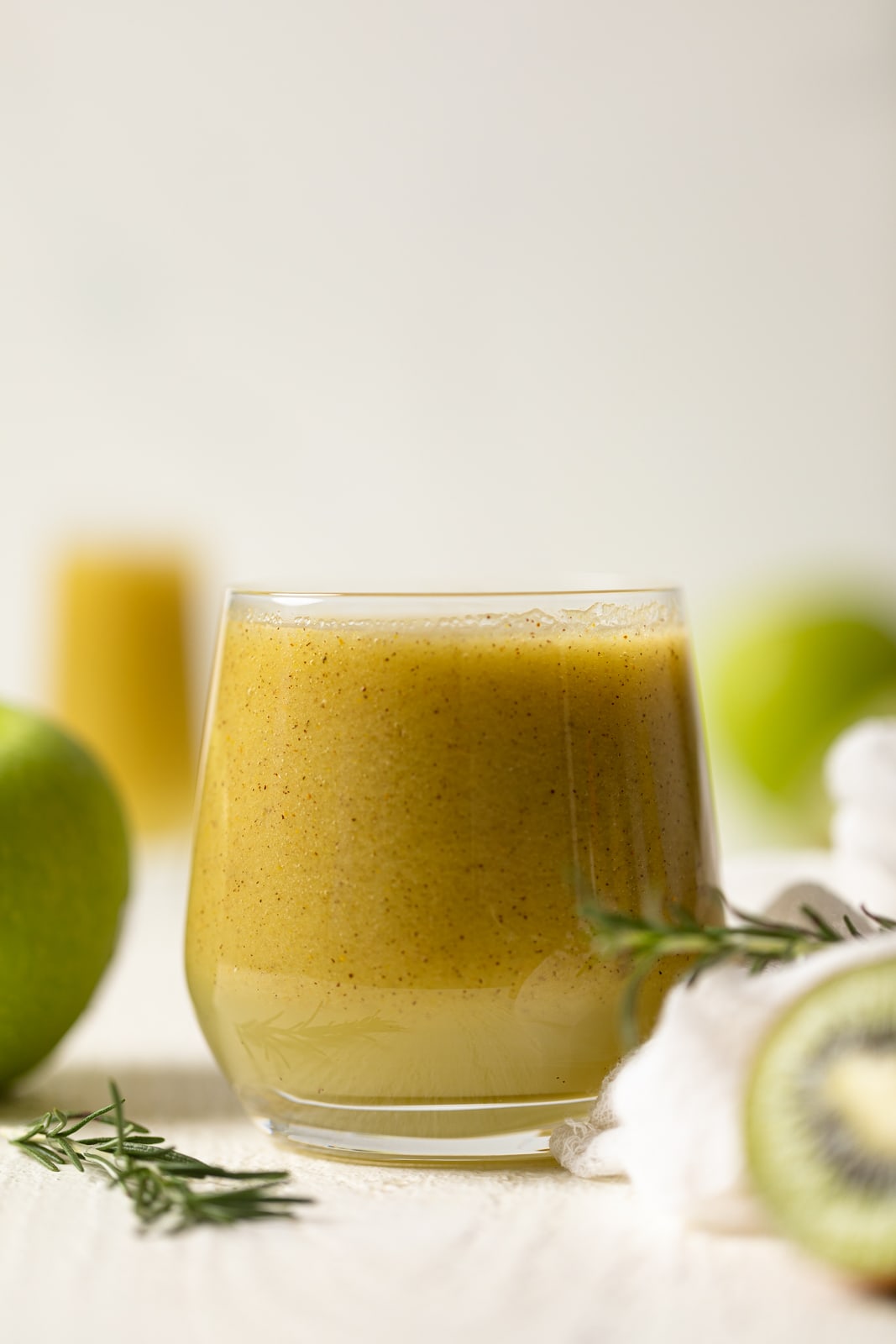 Small glass of Cleansing Apple Kiwi Juice near sprigs of rosemary