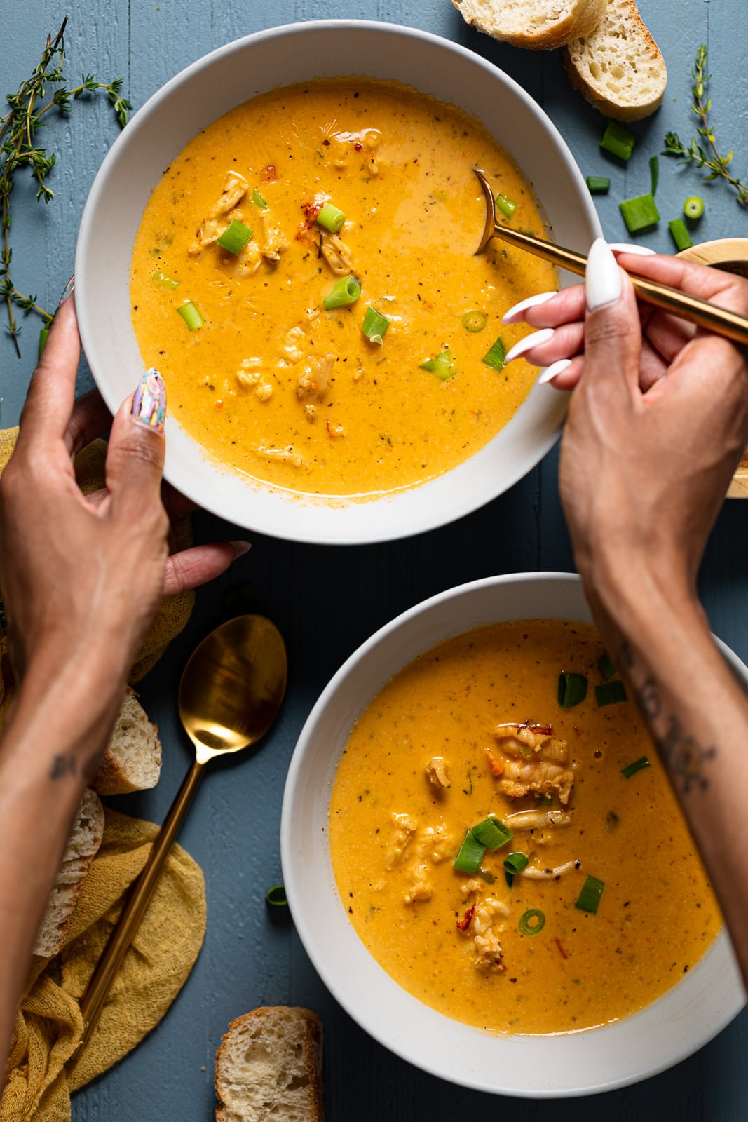 Hand using a spoon to scoop some Creamy Lobster Bisque