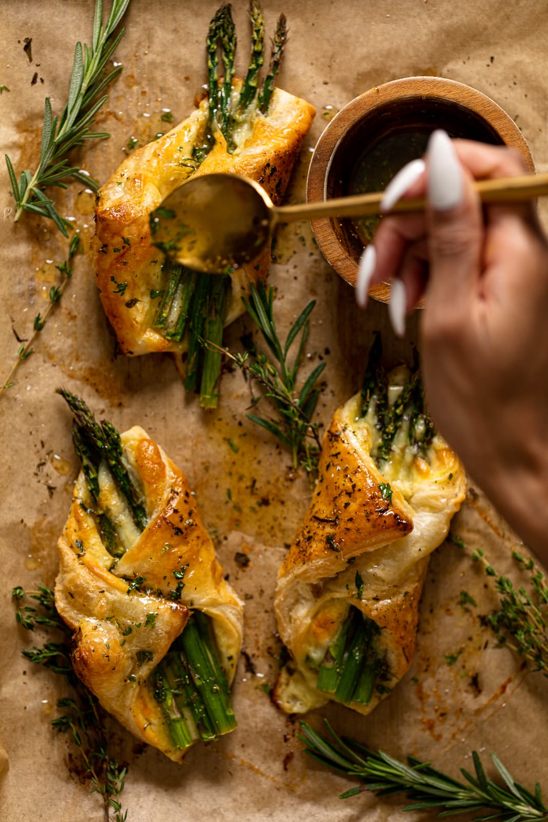 Hand using a spoon to drizzle herb honey on an Asparagus and Mozzarella Puff Pastry