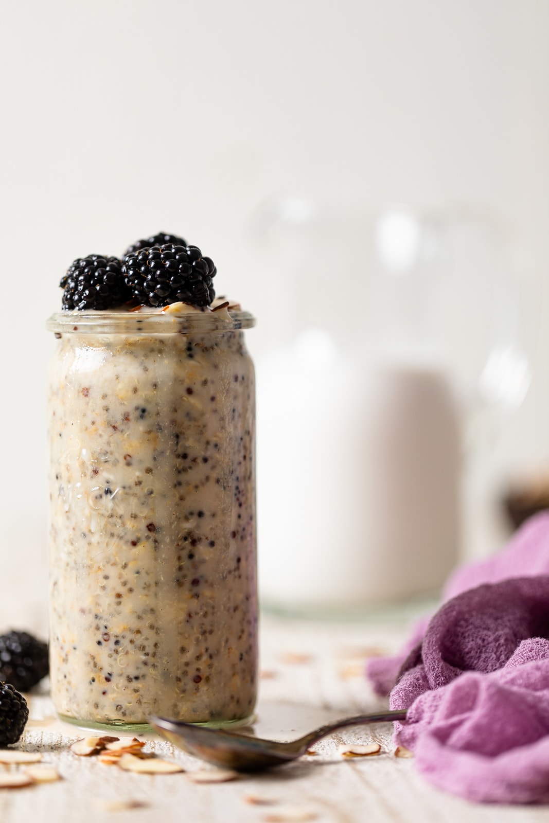 Glass of Protein Overnight Quinoa topped with blackberries behind a spoon