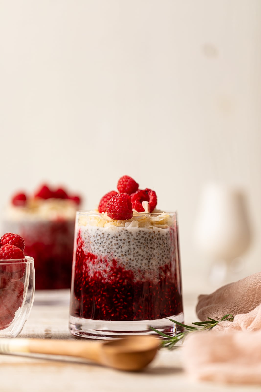 Small glass of Coconut Raspberry Chia Pudding topped with raspberries