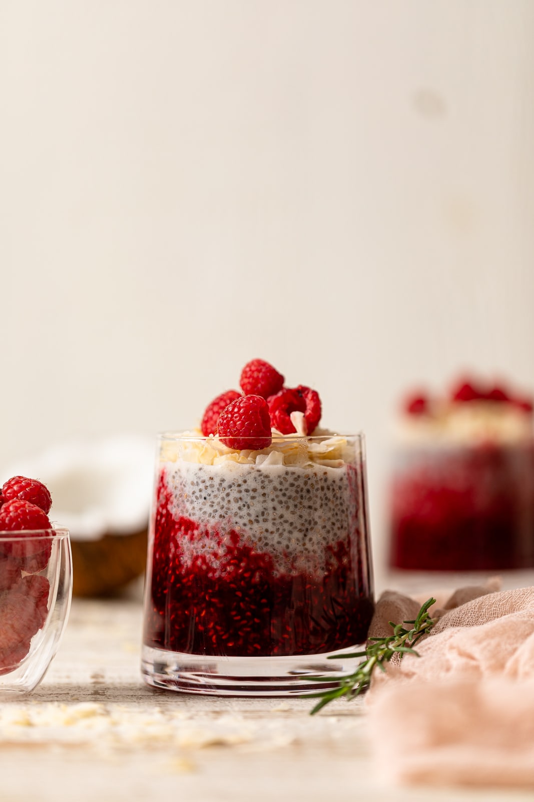 Small glass of Coconut Raspberry Chia Pudding topped with raspberries