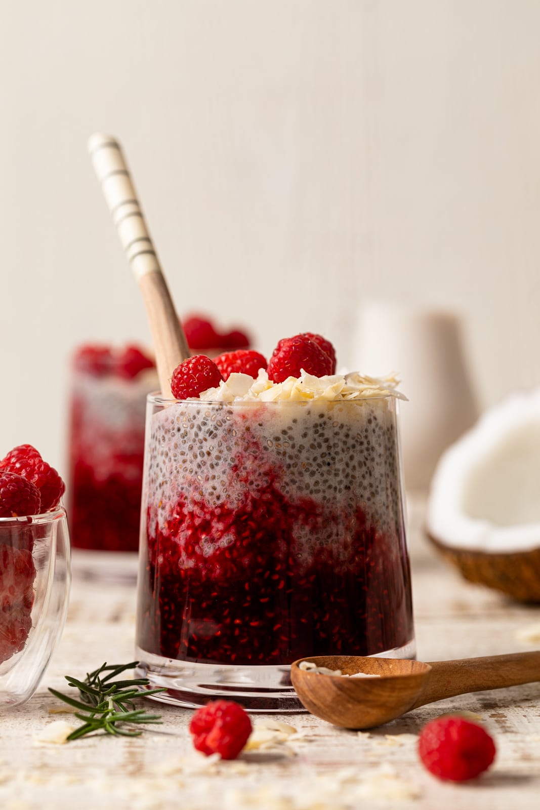 Glass of Coconut Raspberry Chia Pudding with a wooden spoon