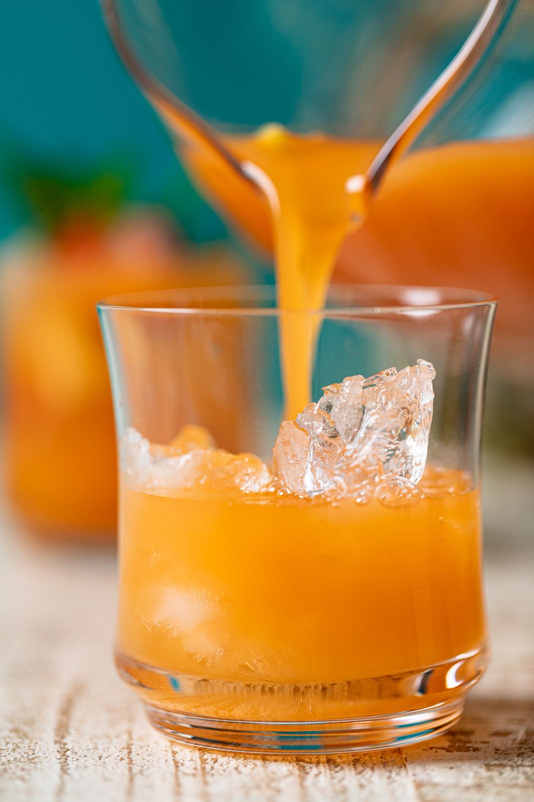 Jamaican Rum Punch Mocktail pouring from a pitcher into a glass of ice