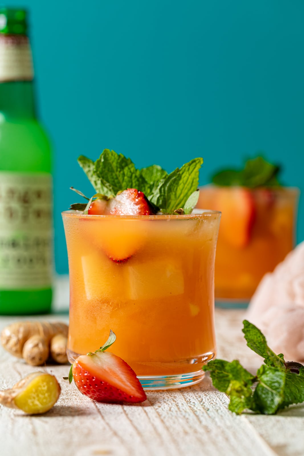 Glass of Jamaican Rum Punch Mocktail surrounded by strawberries and ginger