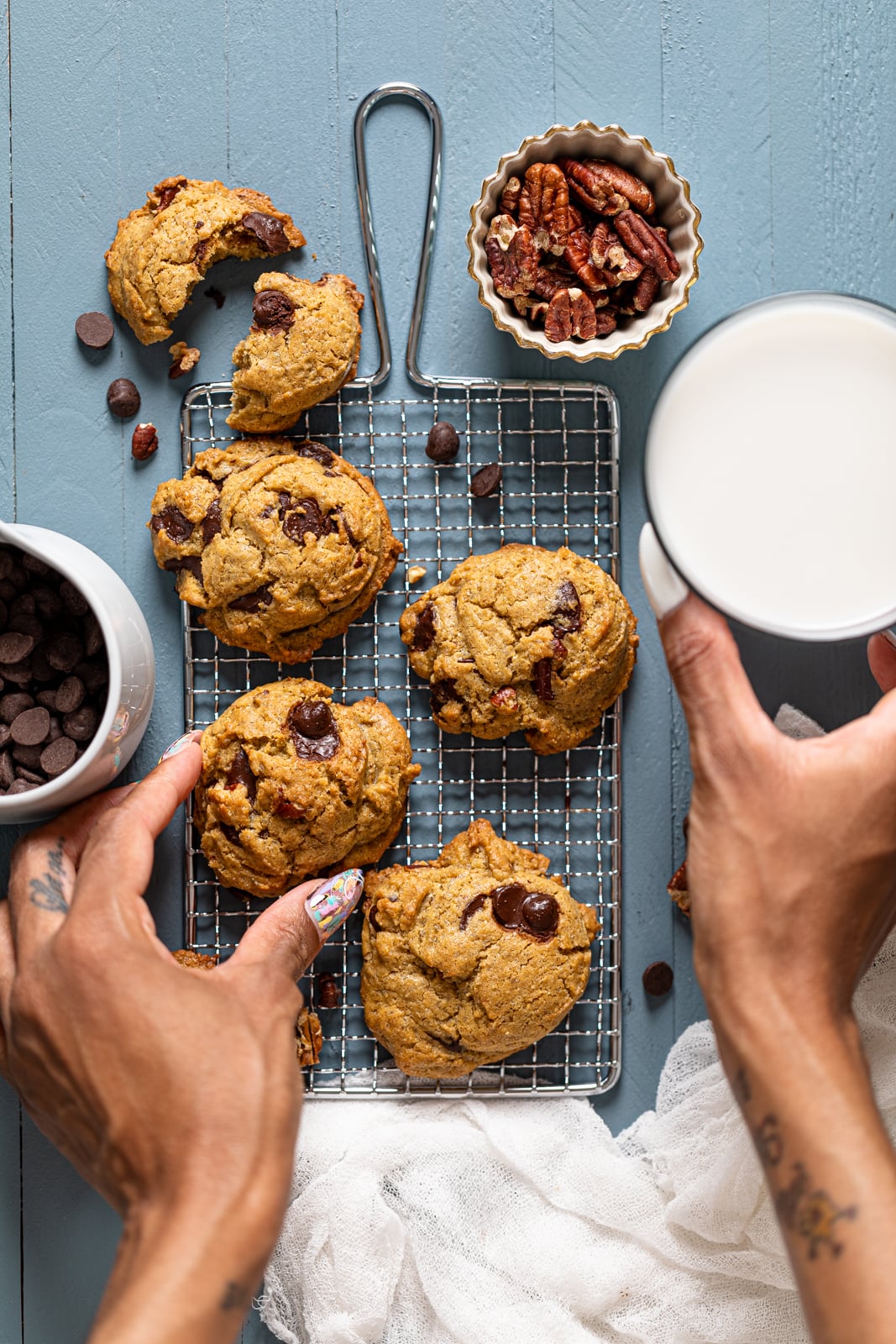 Hand grabbing an Espresso Rye Pecan Chocolate Chip Cookie from a wire rack