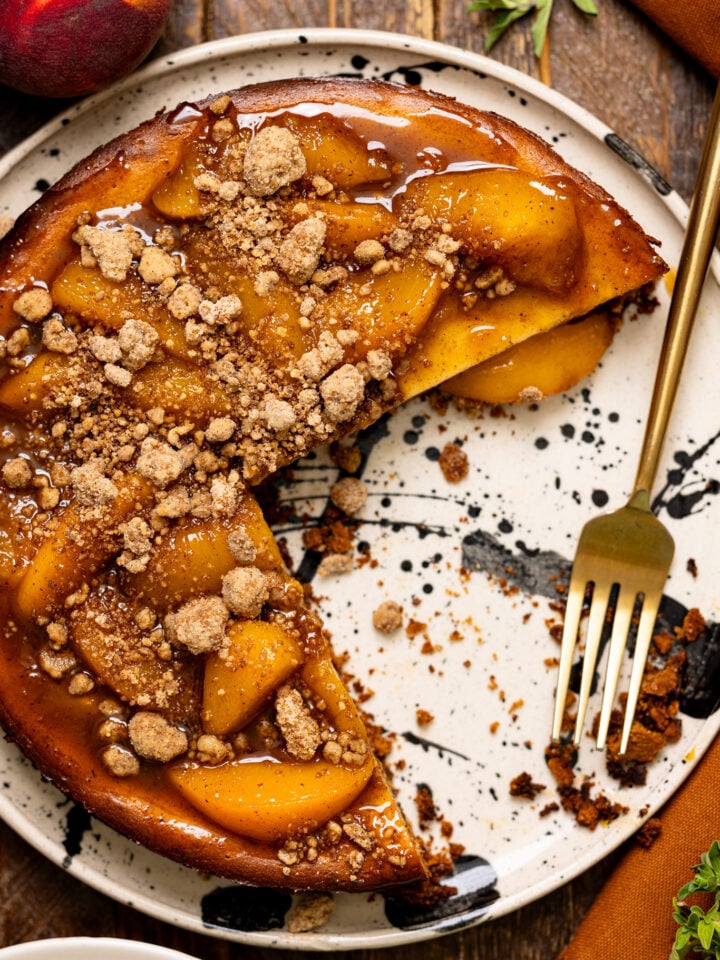 Southern Peach Cobbler Cheesecake sliced on a platter with fork.