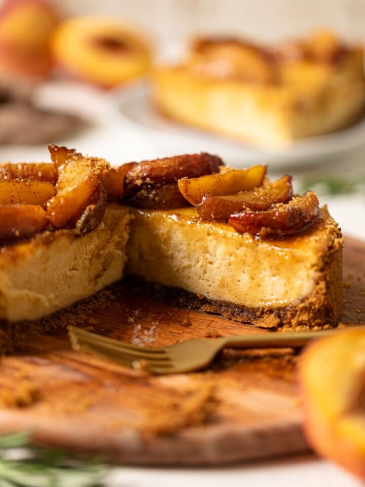 Southern Peach Cobbler Cheesecake missing a slice on a wooden board
