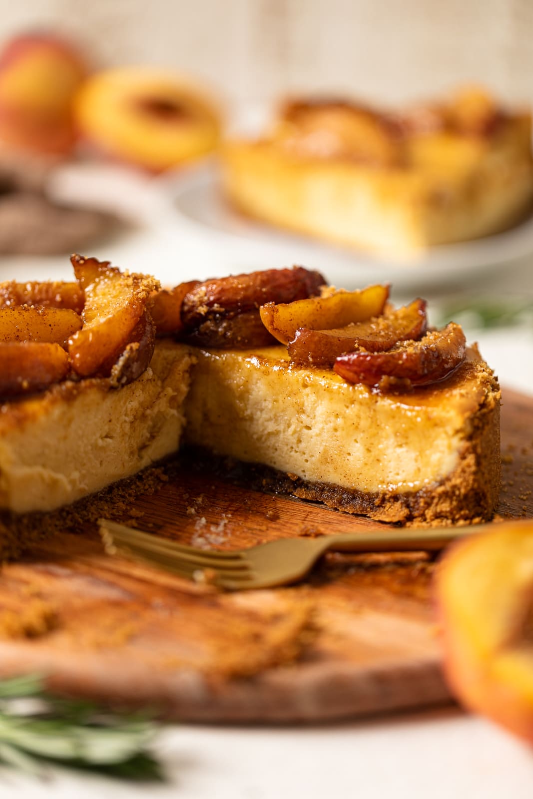 Southern Peach Cobbler Cheesecake missing a slice on a wooden board. A classsic southern comfort food recipe!