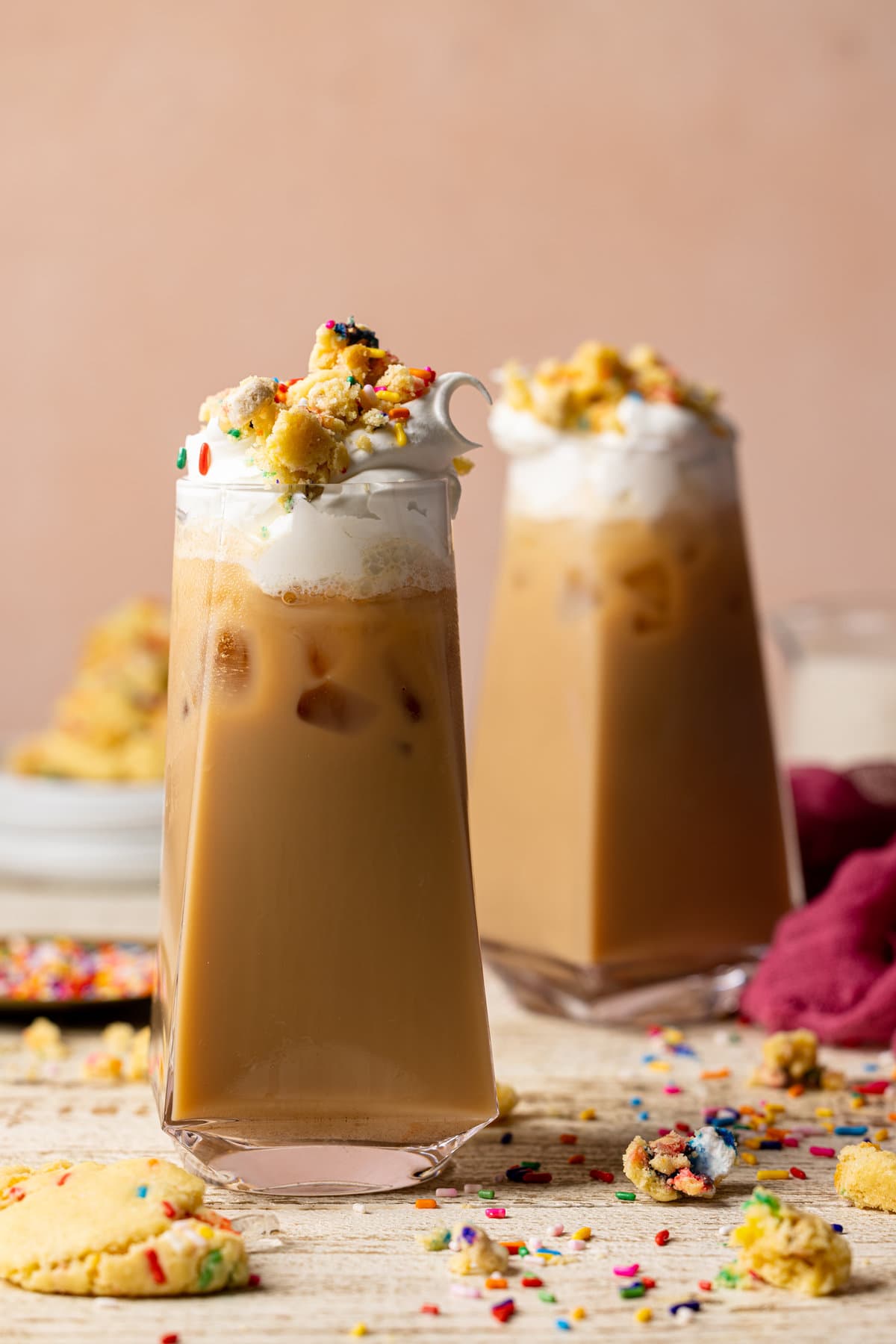 Two glasses of Starbucks Copycat Iced Sugar Cookie Lattes topped with cookie bits