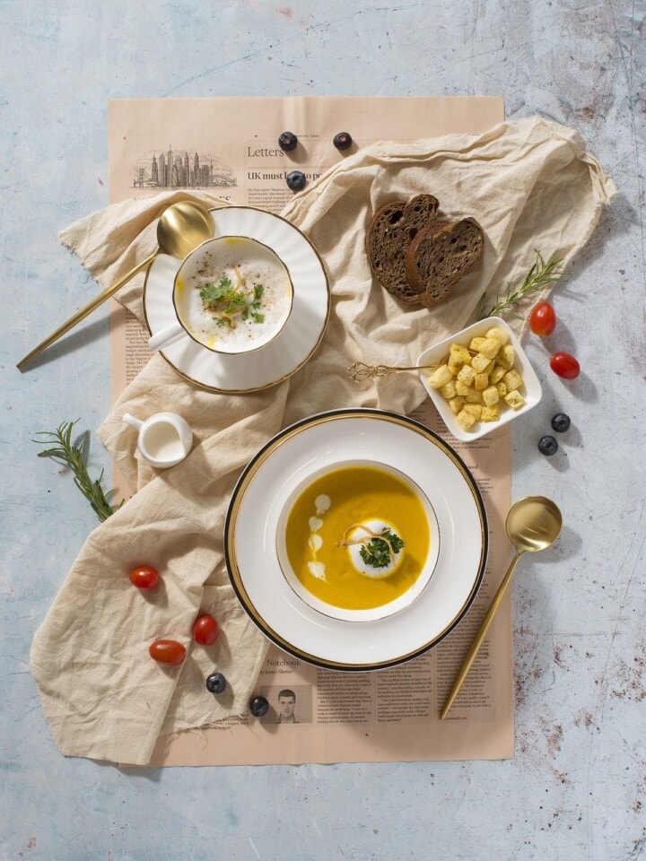 Overhead shot of plates and bowls of various foods on a canvas sheet and newspaper
