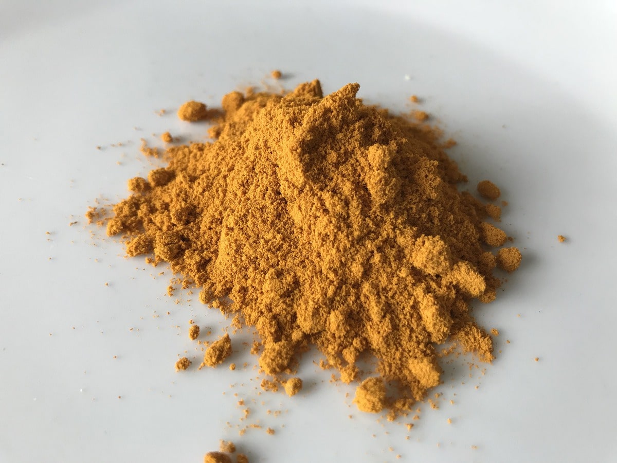 Pile of turmeric on a white surface