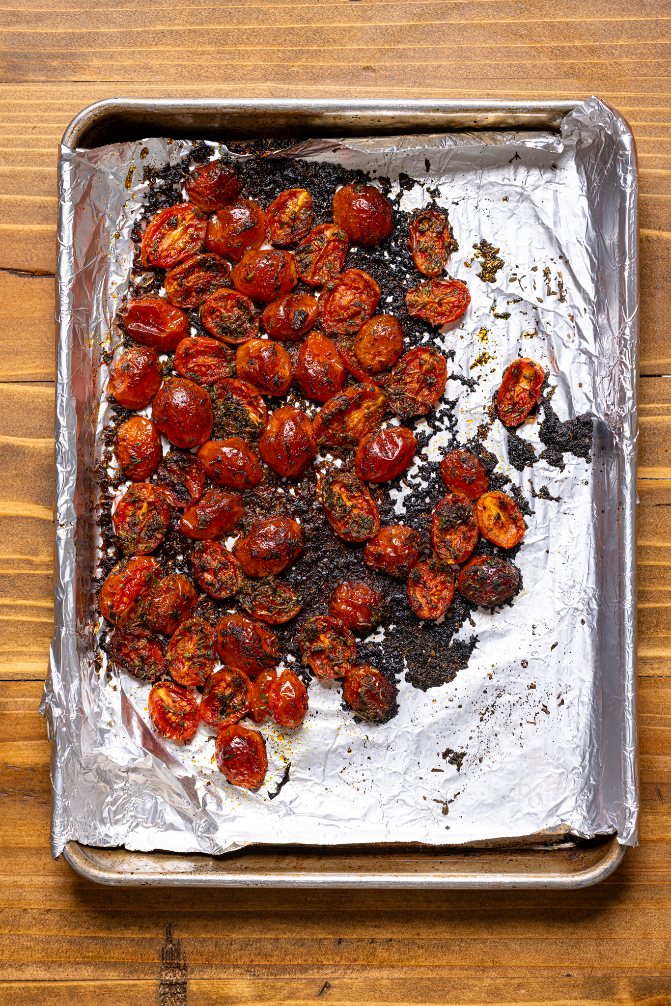 Image of roasted tomatoes atop a baking sheet with foil paper.