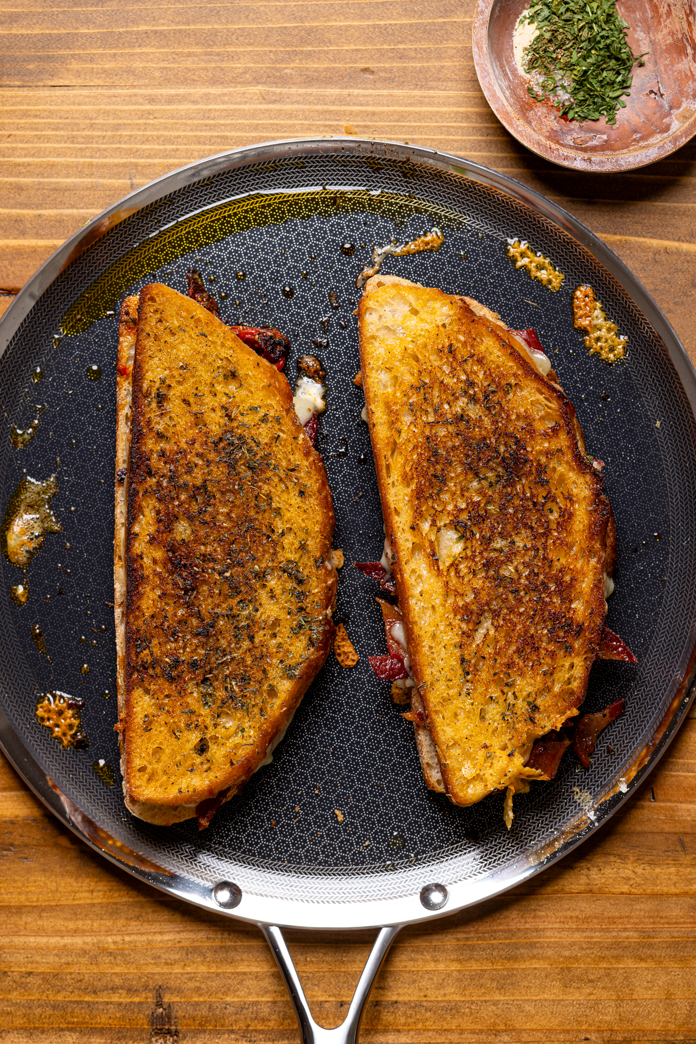 Image of grilled cheese sandwiches on a griddle atop a wood table.