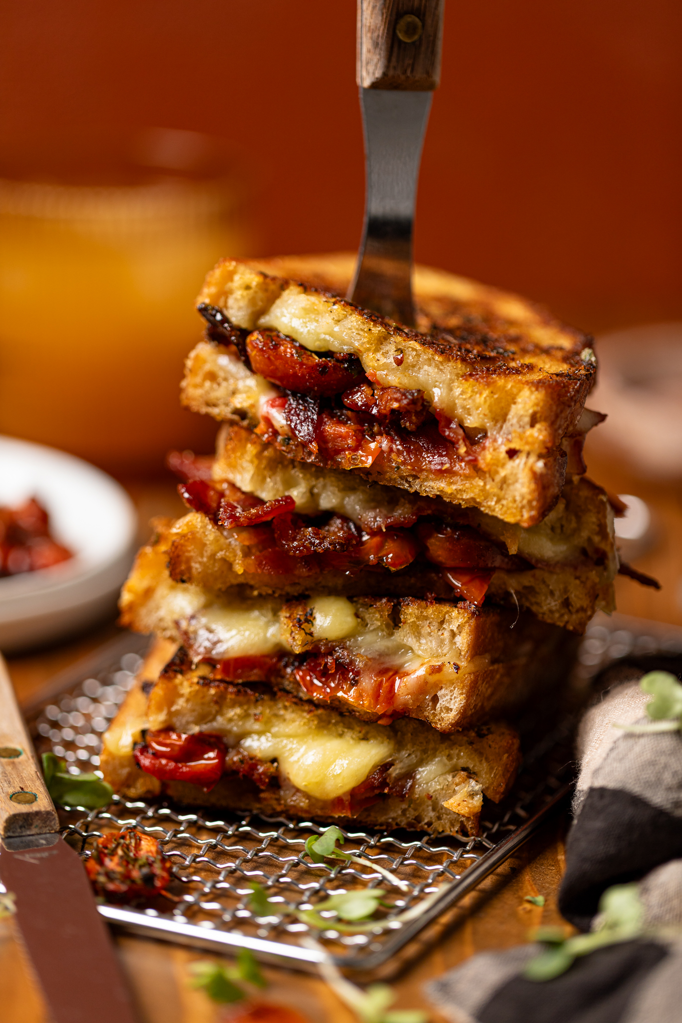 Bacon grilled cheese sandwiches stacked on each with a fork through the top.