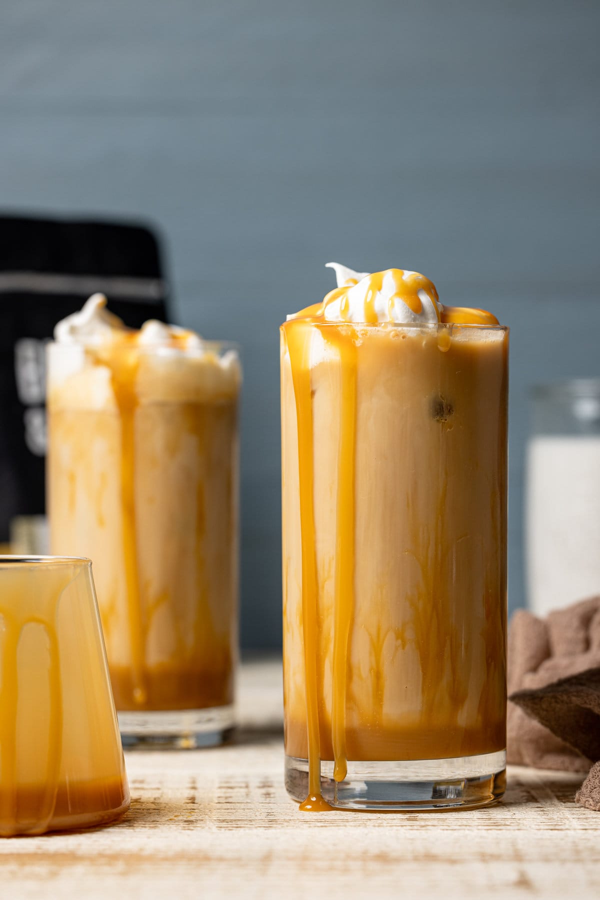 Two Iced Caramel Lattes with caramel dripping down the sides of the glasses